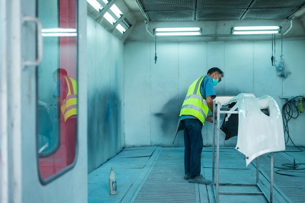 Adult Asian man is using painting gun in repair mechanic painting shop