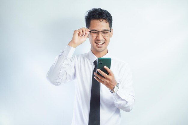 Photo adult asian man laughing out loud when looking to his mobile phone