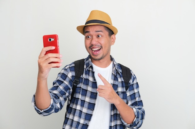 Adult Asian man looking and pointing to handphone that he hold with excited expression