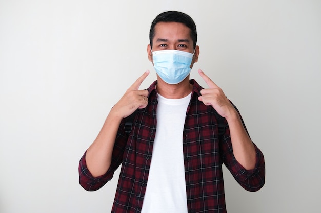 그의 보호 의료 마스크를 가리키는 성인 아시아 남자