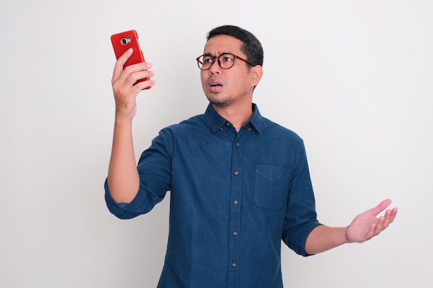 Photo adult asian man searching for phone signal with confused expression