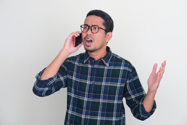 Adult Asian man showing angry expression when answering a mobile phone call