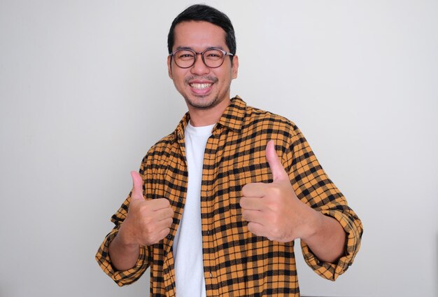 Adult Asian man showing cheerful expression and give two thumbs up