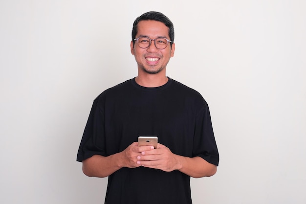 Photo adult asian man smiling happy while holding mobile phone