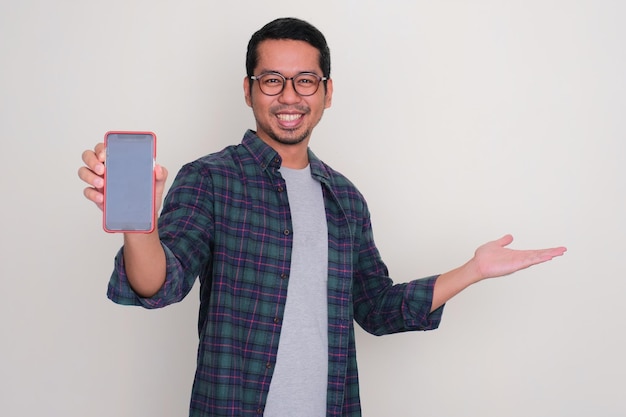 Photo adult asian man smiling and showing blank handphone screen