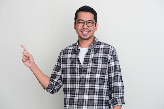 Adult Asian man smiling while pointing to the right