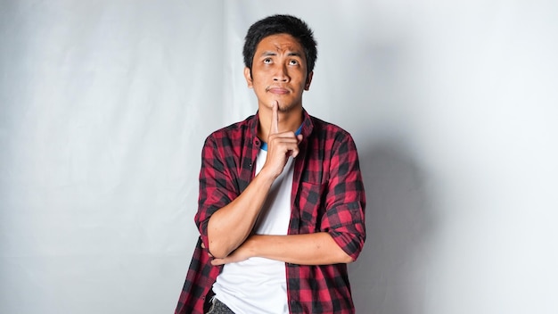 Photo adult asian man wearing red flannel shirt showing thinking gesture