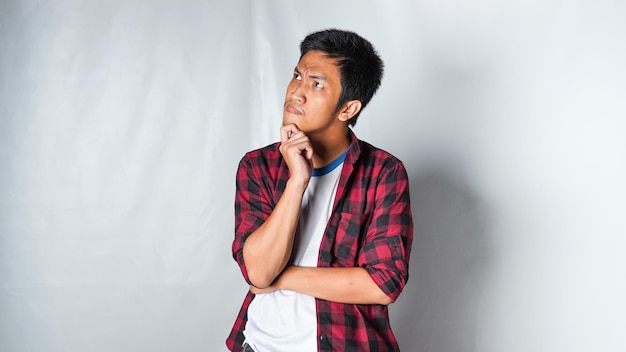 Photo adult asian man wearing red flannel shirt showing thinking gesture