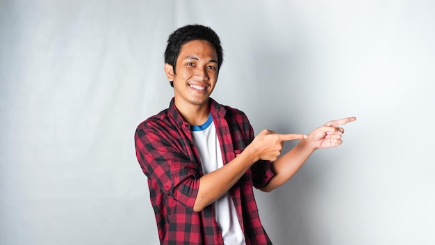 Foto uomo asiatico adulto che indossa una maglietta di flanella rossa che indica l'area destra con la faccia sorridente isolata su sfondo bianco