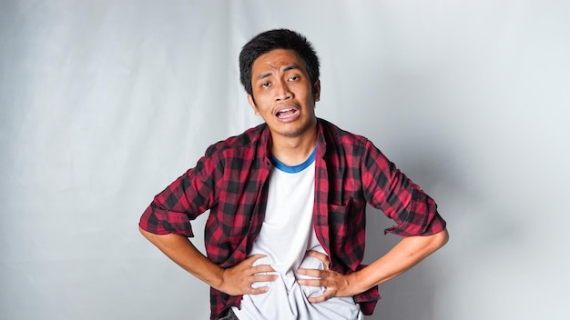 Foto uomo asiatico adulto che indossa una maglietta di flanella rossa malattia dello stomaco isolato su sfondo bianco