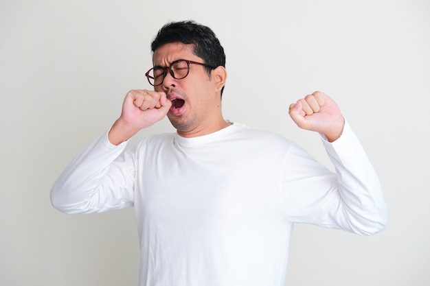 Adult Asian man yawning and stretching his muscles