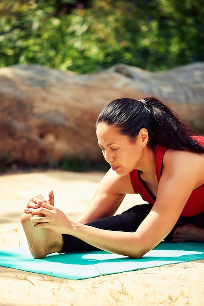 Adult asian woman doing yoga in nature doing stretching and flexibility exercises yoga class for adult women