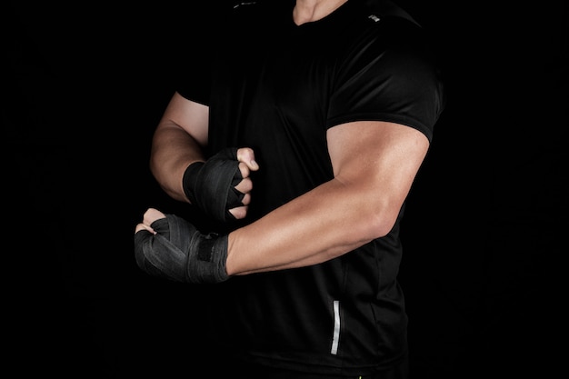 Взрослый спортсмен в черной униформе стоит в стойке с напряженными мышцами