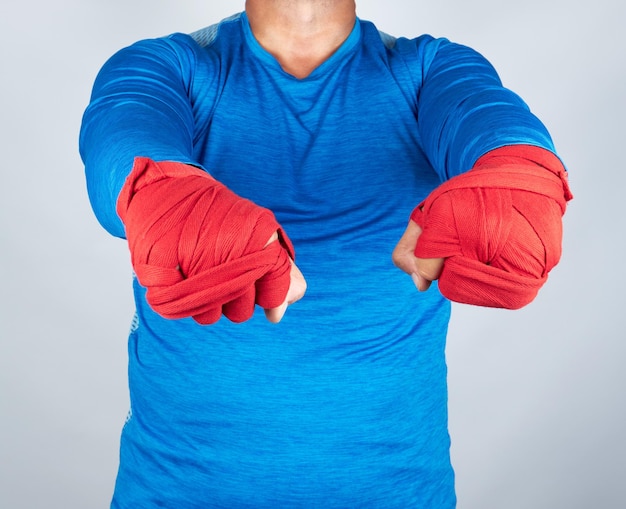 Фото Взрослый спортсмен в синей одежде с руками, обернутыми в красную эластичную повязку