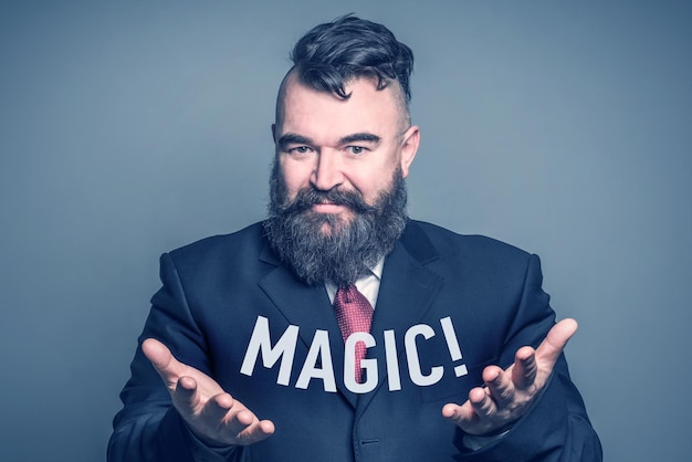 写真 碑文「magic」を持つスーツを着たひげを生やした大人の男性