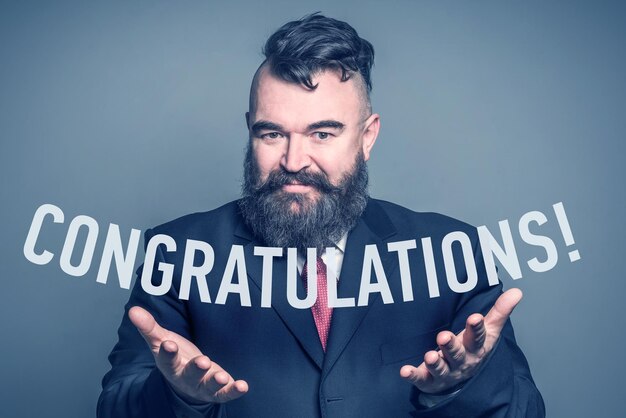 Adult bearded man in a suit holding the inscription CONGRATULATION