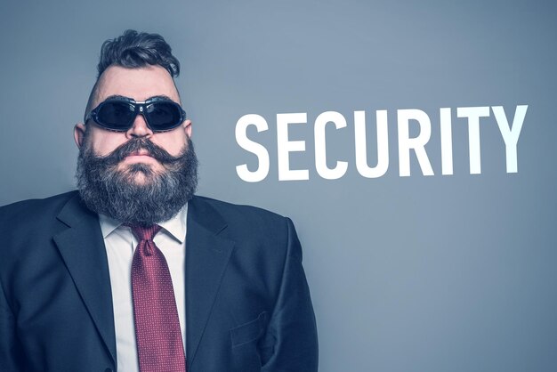 Adult bearded man in a suit and sunglasses next to inscription SECURITY