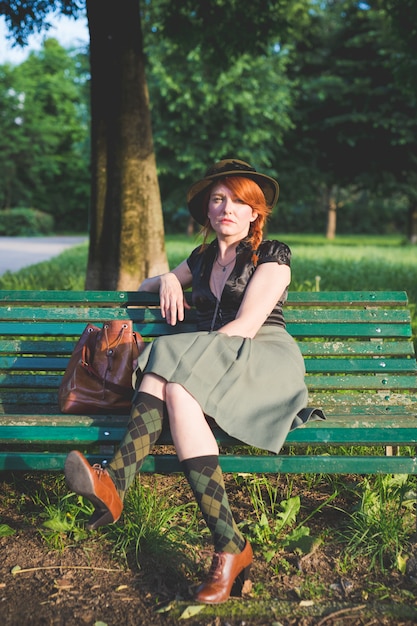 Adult beautiful woman sitting bench outdoor looking camera