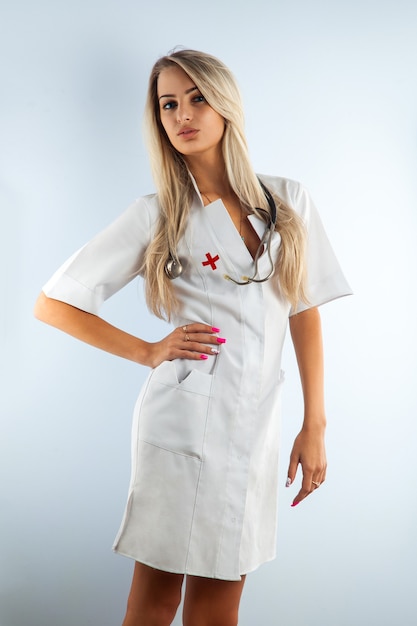 Adult blonde beautiful nurse in white medical gown