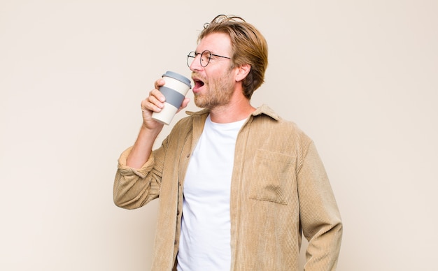 Adult blonde man holding a hot coffee