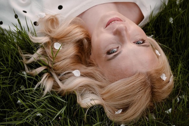 Adult blonde woman portrait from above on the green grass