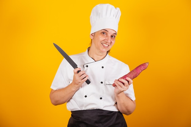 Adult brazilian woman chef master in gastronomy holding sweet potato and knife