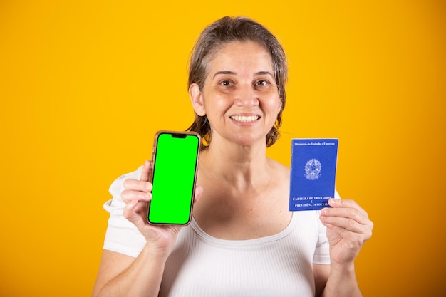 Взрослая бразильская женщина держит смартфон с рабочей картой и картой социального обеспечения с зеленым экраном