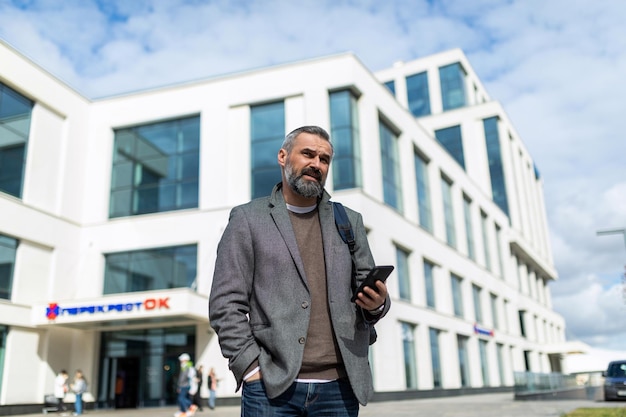 Adult business businessman years old against the background of a business center with a mobile phone