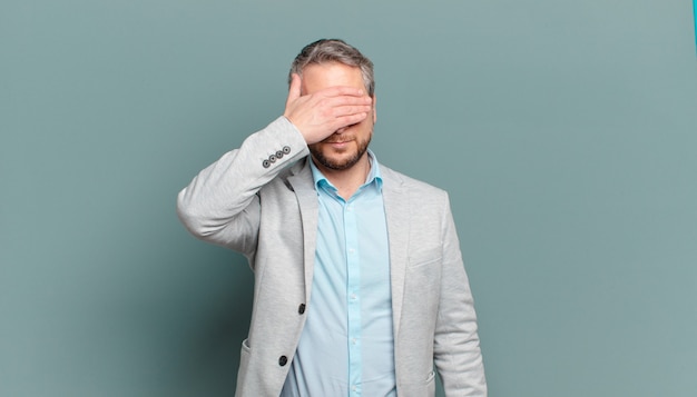 Adult businessman covering eyes with one hand feeling scared or anxious