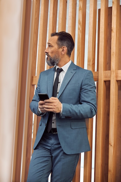 Adult businessman using smartphone in a modern office