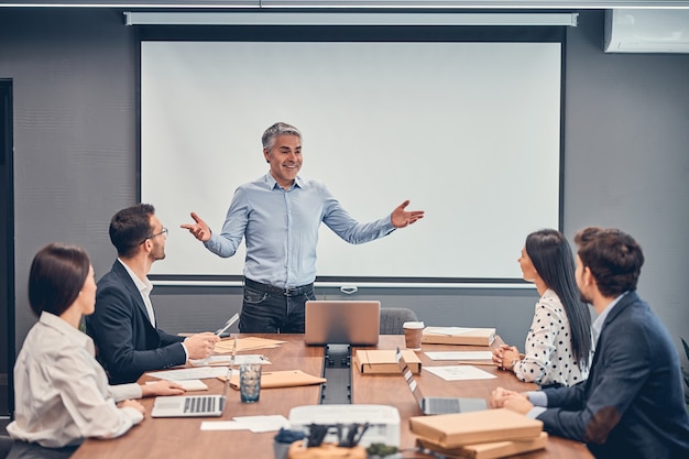 Adult businessman welcoming his team at the meeting