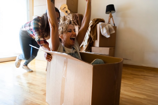 Adult caucasian woman having fun with cardboard moving boxes Mature female laughing Relocation