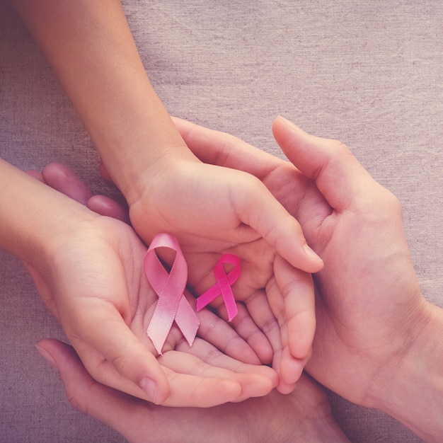 Adult and child hands holding pink ribbons