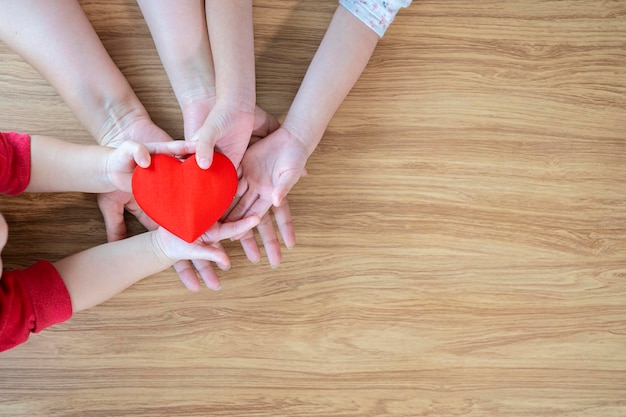 Adult and child hands holding red heart on aqua background heart health donation CSR concept world heart day world health day family day