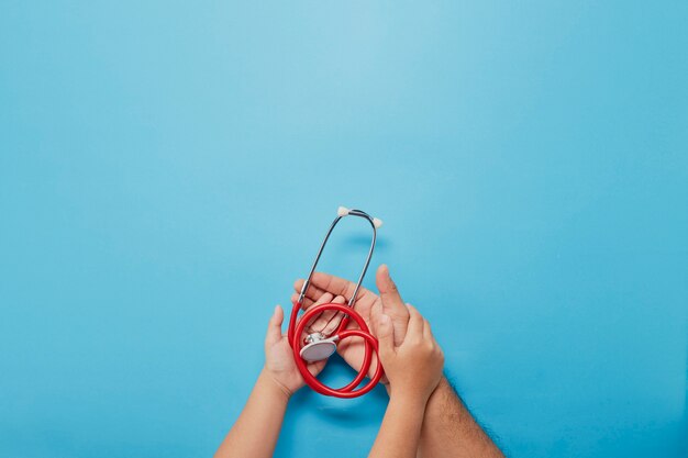 Adult and child hands holding red stethoscope