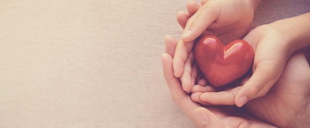 Foto mani del bambino e dell'adulto che holiding rosso lui, lui concetto di salute e di donazione