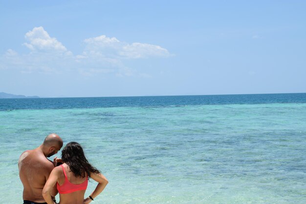 Adult couple at the beach watching their photos on the cell phone