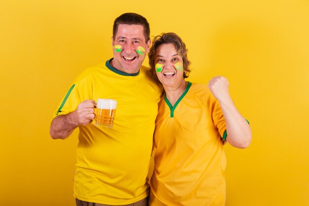 Adult couple soccer fan from brazil cheering holding beer