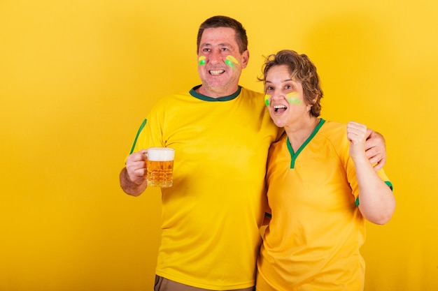 Adult couple soccer fan from brazil cheering holding beer