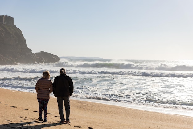 An adult couple walking on the beach