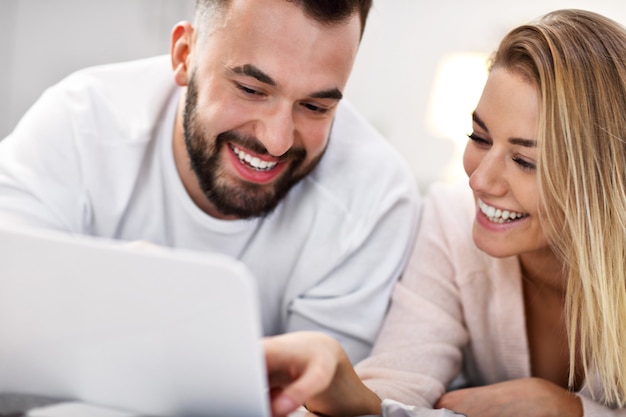 Coppia adulta con computer portatile a letto