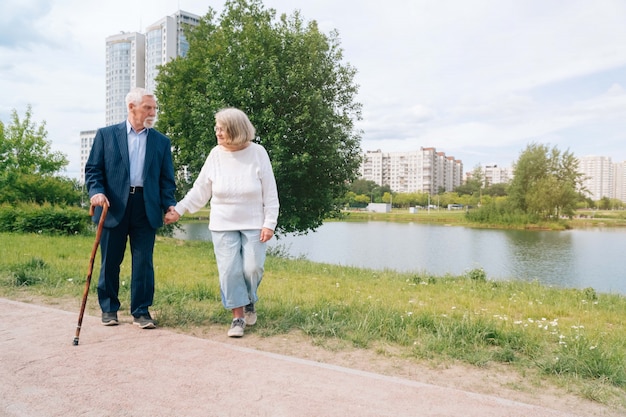 An adult European couple walks around the city. A walk in the fresh air grandparents go by the hand in urban.