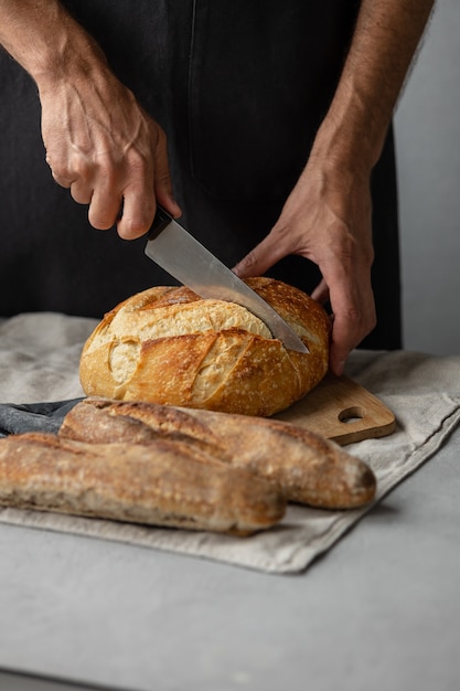 An adult european male baker holds a round fresh bread in his hands a man in a bakery holds a