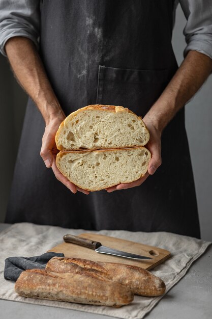 An adult european male baker holds a round fresh bread in his hands a man in a bakery holds a