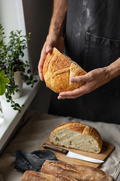 An adult european male baker holds a round fresh bread in his hands a man in a bakery holds a