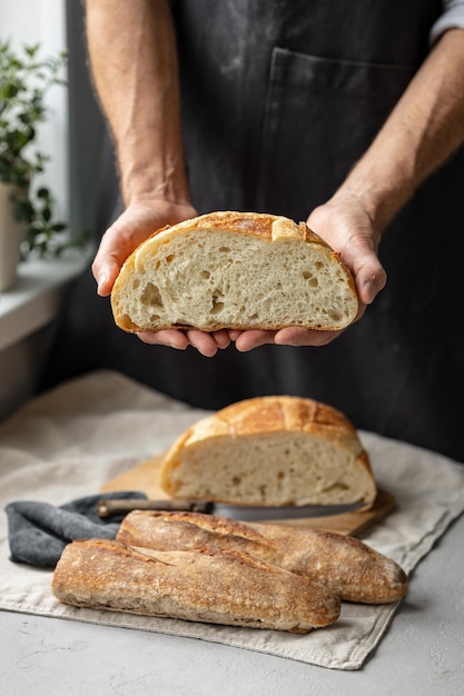 An adult european male baker holds a round fresh bread in his hands a man in a bakery holds a