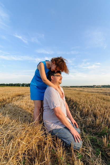 大人の農夫と妻は畑で時間を過ごします。男は座っています。女性が彼の隣に立ち、抱擁します。女性が夫の頭にキスをする。