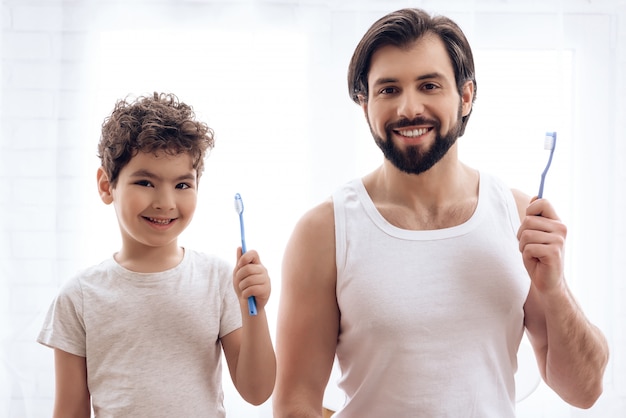 Adult father and son brush their together.