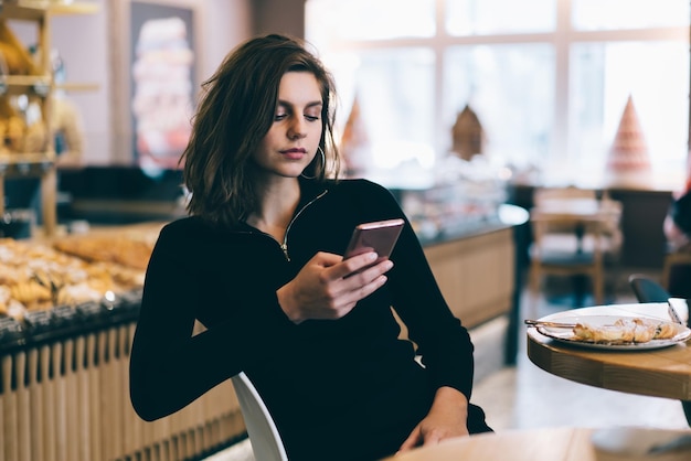 Adult female surfing smartphone at cafe