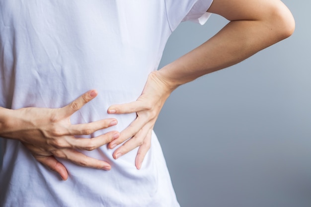 Adult female with muscle pain on gray background. elderly woman having back body ache due to piriformis syndrome, low back pain and spinal compression. sports injuries and medical concept